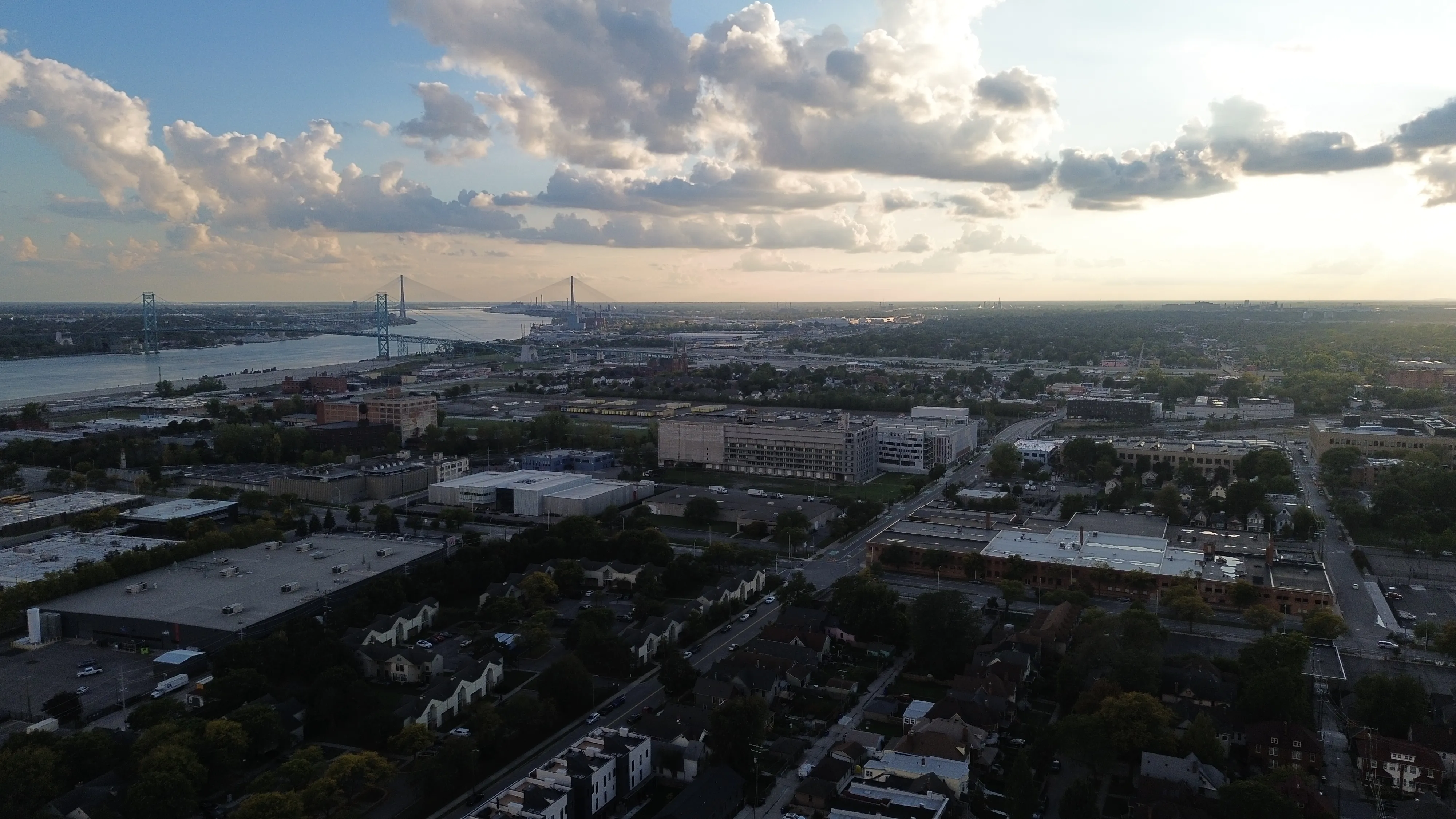 Cloudy evening aerial of Detroit with bridges and industrial buildings stretching toward the horizon.